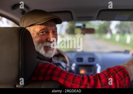 Portrait of senior man driving car in reverse and looking over shoulder Stock Photo
