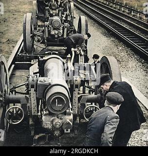 Station porters at a small country station at an undisclosed location in Britain, unloading heavy calibre howitzers from railway trucks. Stock Photo