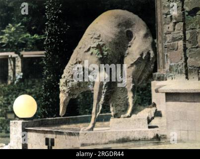 A stone sculpture of a Russian Borzoi dog belonging to King Albert I of Belgium. It is in the form of a garden ornament, showing the dog drinking from a river. Stock Photo