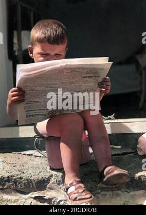 A little boy reads the latest news whilst sitting on his potty! Stock Photo