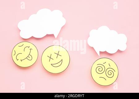 Paper faces with blank speech bubbles on pink background Stock Photo