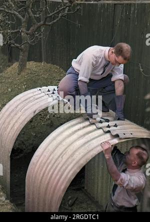 Two men constructing an Anderson shelter in a back garden at the start of the Second World War. Stock Photo