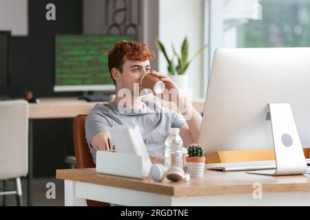 Male programmer drinking coffee at table in office Stock Photo