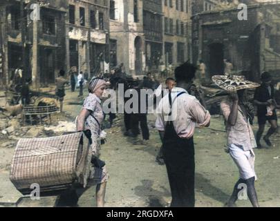 Following a bombardment of Chongqing (Chungking), a Russian woman tries to salvage some of her belongings from the fire. The strangely designed hat is being worn for identification by rescue squads Stock Photo