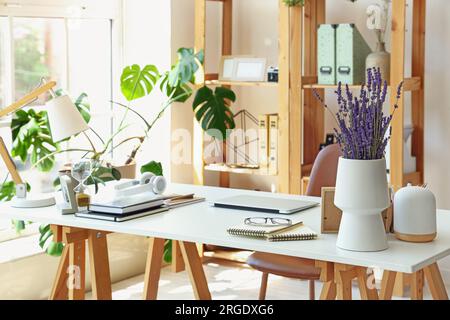 Modern workplace with laptop and lavender flowers in interior of office Stock Photo