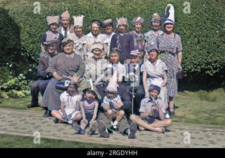 A group of people in party hats, posing for their photo in the sunshine. Stock Photo