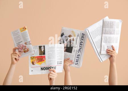 Female hands with different newspapers on color background Stock Photo