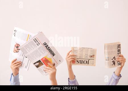 Female hands with different newspapers on light background Stock Photo