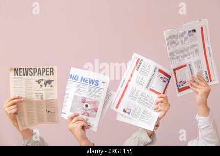 Female hands with different newspapers on color background Stock Photo