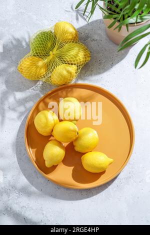 fresh lemons on a yellow plate. hard sunlight and shadows Stock Photo