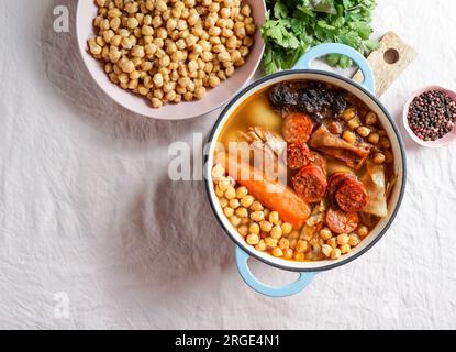 Cocido Madrileño, a traditional Spanish meal, chickpea-based stew from Madrid rose pink ceramic tile background Stock Photo