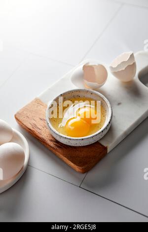 Egg with a double yolk cracked in a small bowl Stock Photo