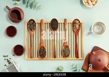 Beautiful set for traditional tea ceremony and tea collection in wooden spoons on light blue background flat lay Stock Photo
