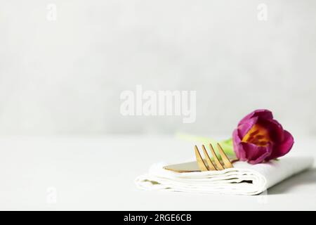 Golden Cutlery set and beautiful flower on light grey table with space for text. Festive table setting Stock Photo