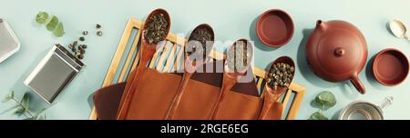 Beautiful set for traditional tea ceremony and tea collection in wooden spoons on light blue background flat lay Stock Photo