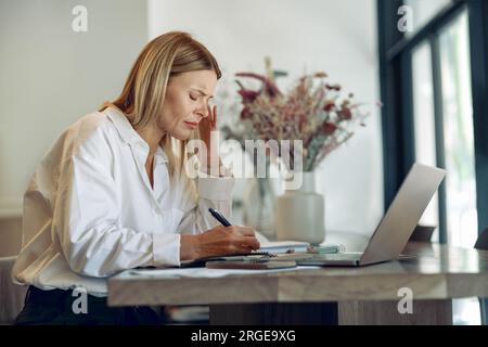 Focused business woman working on laptop, making notes in cozy coworkign space interior Stock Photo