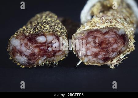 Picture of a fuet sausage sliced and coated in peppercorn. Fuet is a Catalan thin, dry-cured, sausage of pork meat in a pork gut. The most famous is m Stock Photo