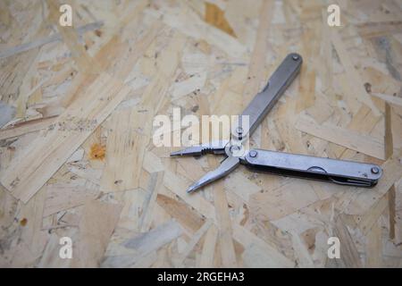 Silver all purpose pocket knife on a rustic wooden background. Top view folding knife with tools Stock Photo