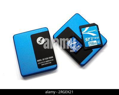 NISSWA, MN – 1 AUG 2023: Closeup of a Sabrent brand 256 GB SD Card on top of one of two cases, viewed from above, isolated on white. Stock Photo