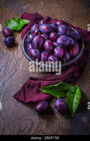Fresh plums on plate over dark wooden background Stock Photo