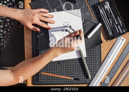 Architect and designer working accurately on a project drawing sketches and technical drafts on paper using professional tools like rulers compass and Stock Photo