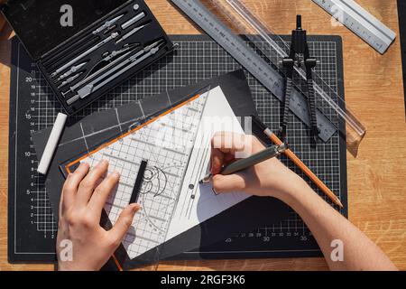 Architect and designer working accurately on a project drawing sketches and technical drafts on paper using professional tools like rulers compass and Stock Photo
