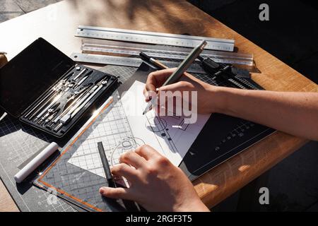 Architect and designer working accurately on a project drawing sketches and technical drafts on paper using professional tools like rulers compass and Stock Photo