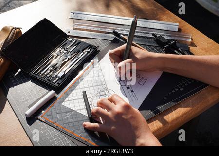 Architect and designer working accurately on a project drawing sketches and technical drafts on paper using professional tools like rulers compass and Stock Photo