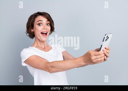 Portrait of impressed overjoyed person open mouth unbelievable internet speed hold smart phone isolated on grey color background Stock Photo