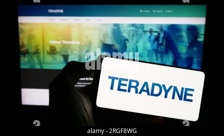 Person holding smartphone with logo of US test equipment company Teradyne Inc. on screen in front of website. Focus on phone display. Stock Photo