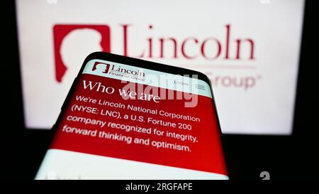 Smartphone with website of US financial company Lincoln National Corporation on screen in front of logo. Focus on top-left of phone display. Stock Photo