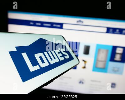 Smartphone with logo of American retail company Lowe's Companies Inc. on screen in front of website. Focus on center-left of phone display. Stock Photo