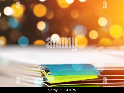 Stack documents on the desk in the office and a background of golden Christmas lights and garland in background Stock Photo