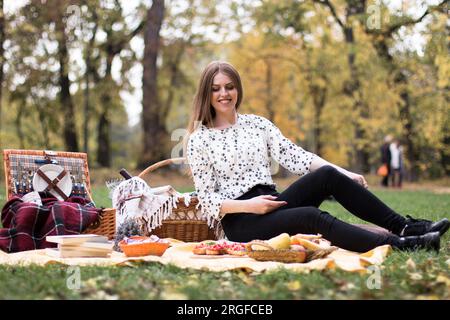 Young beautiful ginger haired woman on a picnic in the park, waiting for her friends to arrive. Stock Photo