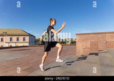 A young woman in black clothes running on stairs at city street early morning. Stock Photo