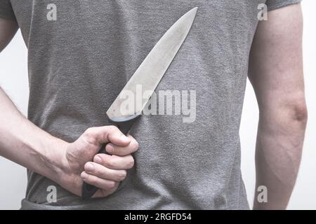 AMan holding a kitchen knife behind his back. Stock Photo