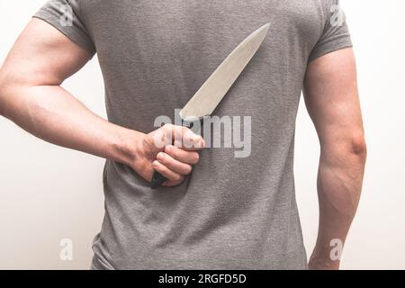AMan holding a kitchen knife behind his back. Stock Photo
