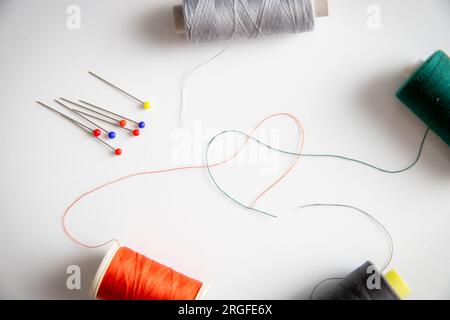sewing thread forming a shape of heart with some other sewing equipment on the picture. Stock Photo