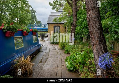 London, UK: Houseboat at Blomberg Road Moorings on Regent's Canal in London, part of the area known as Little Venice. With flowers and trees. Stock Photo