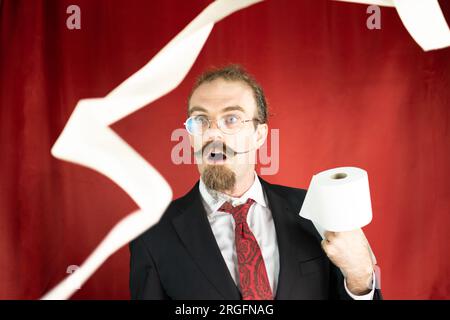 Shocked man with glasses, red tie and toilet paper in hand looking how it fly Stock Photo