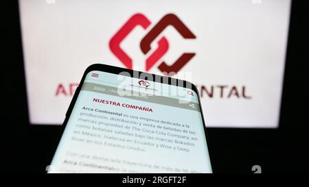 Mobile phone with website of company Arca Continental S.A.B. de C.V. on screen in front of business logo. Focus on top-left of phone display. Stock Photo