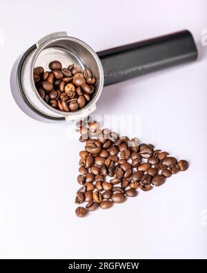 Coffee beans are in a boom arm for coffee machine and on a white table Stock Photo