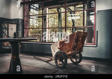 Rusty wheelbarrow in old factory building Stock Photo
