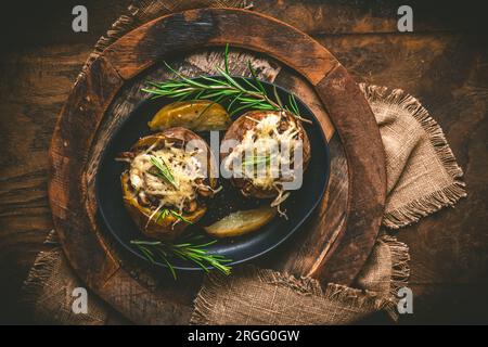 Two baked potatoes with mushrooms, sour cream and cheese on a rustic wooden background, top view, Stock Photo