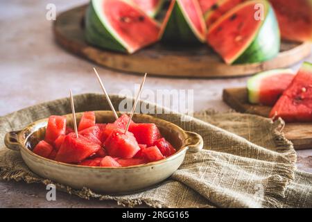Pieces of watermelon as finger food on a plate, sliced watermelon in the background Stock Photo