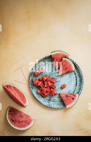 Sliced and chunky fresh watermelon on a green plate on a yellow background, top view with copy space Stock Photo
