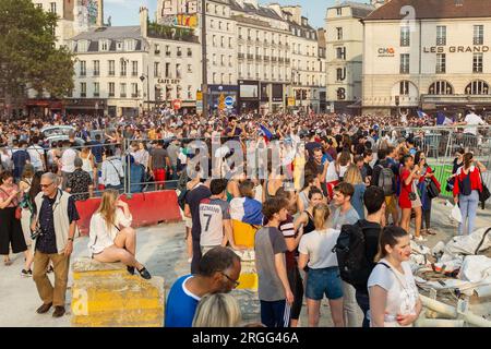 Paris, France, 2018. A preppy blonde is sitting on a concrete block amid the happy chaos place de la Bastille, the day France won the soccer World Cup Stock Photo