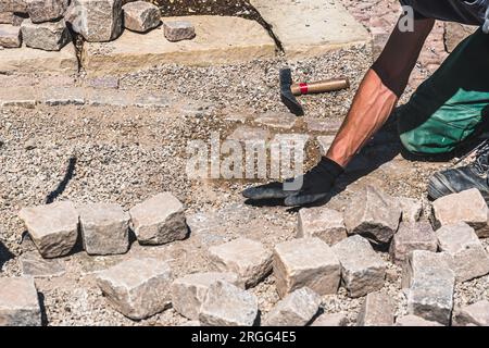 Man lays paving stones for a footpath in a garden Stock Photo