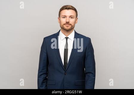 Young businessman in business office suit isolated on gray background. Inexperienced newbie employee Stock Photo