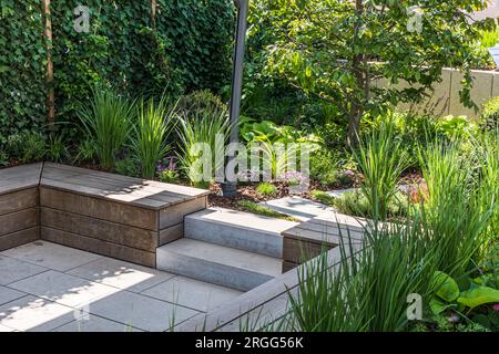 Cozy shady seating area made of concrete and wood in a garden Stock Photo